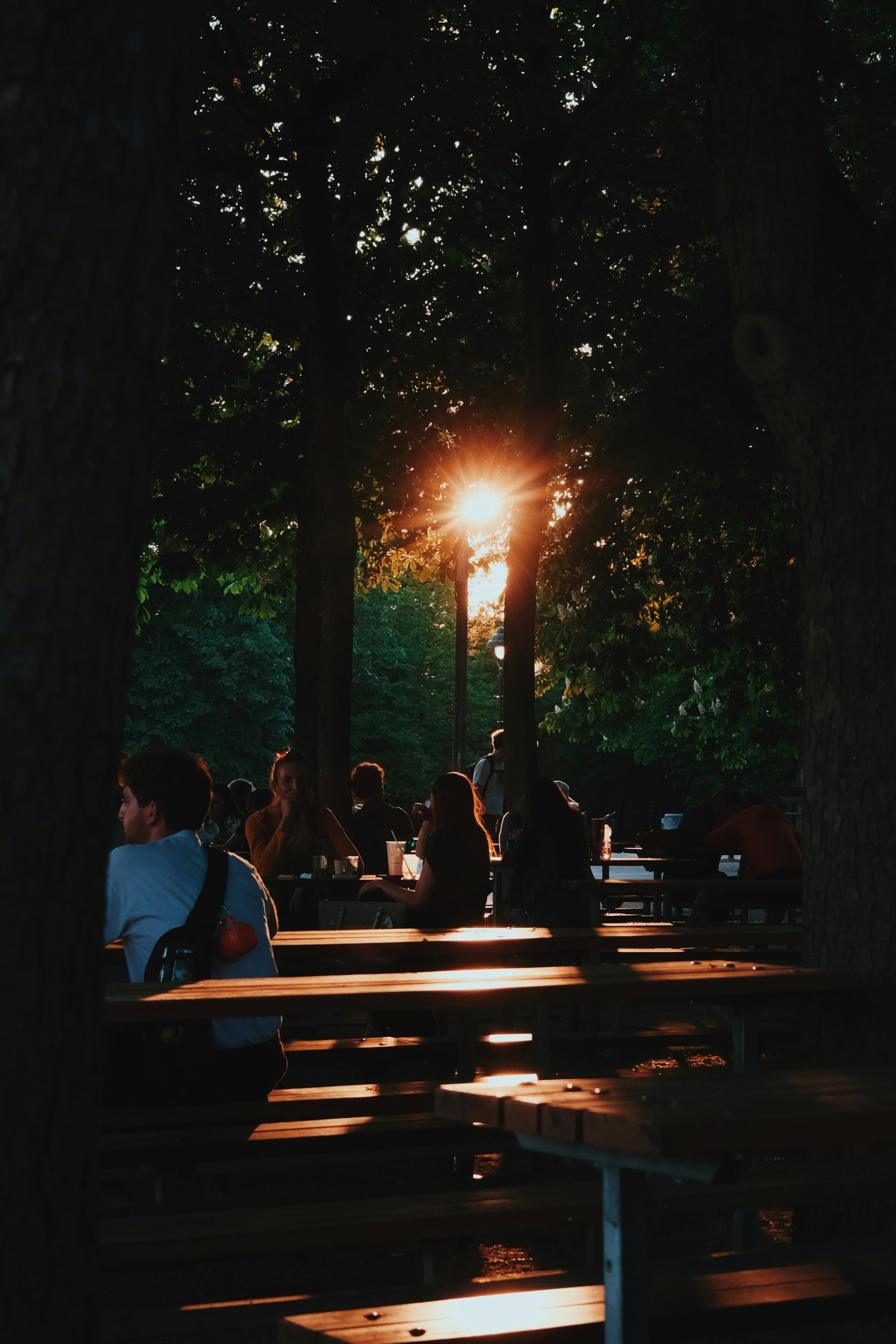 Gäste sitzen auf Holzbänken im Biergarten